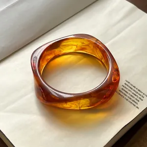 Detailed view of amber resin bangle with smoke pattern on a vintage book page