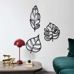 Détail de trois feuilles en métal noir pour décoration murale dans un salon moderne