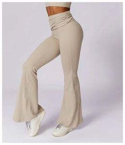 Detail of high-waisted beige flare yoga pants with pleated waistband and slim fit cut