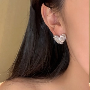 Elegant silver heart earrings with pavé zircons worn by a model for a luxury look