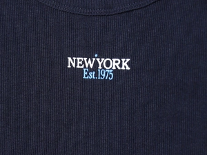 Detail of New York Est. 1975 print on dark blue ribbed knit fabric sweatshirt top