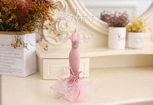 Detailed close-up of a pink mannequin jewelry stand with elegant lace and metal hooks