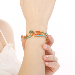 Detailed close-up of gold stainless steel bangle with ocean charms and enamel details