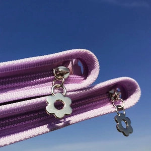 Detail of silver flower zipper pull on a purple jewelry organizer binder with PVC bags