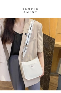 Details der weißen Tasche aus Leder mit Litschimuster und geometrischem Schultergurt