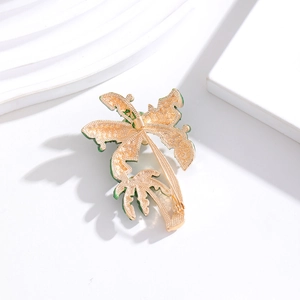 Golden coconut tree brooch with green enamel edges and pin back on white stone
