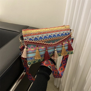 Detail of bohemian woven bag with colorful fringes and embroidered guitar strap