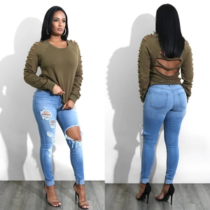 Dettaglio di jeans skinny strappati e felpa verde oliva consumata su una modella