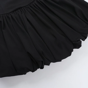 Detail of black tube mini dress showing intricate pleated bubble hem and woven fabric texture