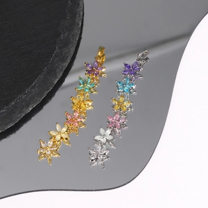 Detailed close-up of flower pendants in gold and silver with colorful zircon inlays