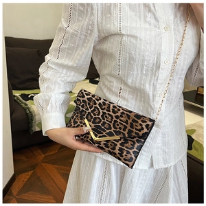 Detail of leopard print crossbody bag with gold V-metal trim and chain strap