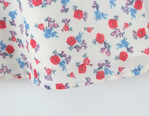 Detail of floral embroidery on white fabric showing red and purple flower patterns