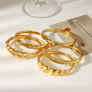 Stack of gold titanium steel bracelets including bamboo, chain, and wave designs