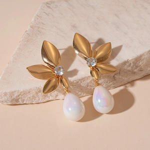 Elegant gold flower earrings with sparkling crystals and teardrop pearls on marble