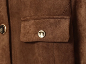 Détail macro du tissu en daim marron avec bouton doré sur le rabat de la poche