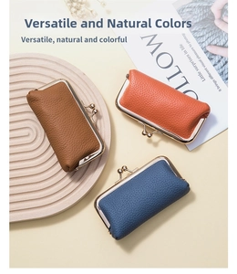 Three leather kiss-lock coin purses in brown, orange and blue on a wooden tray