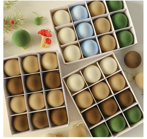 Detail of velvet Christmas baubles in Morandi colors with golden hooks and gift box packaging