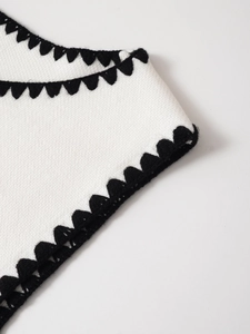 Nahaufnahme von weißem Strickstoff mit schwarzer Häkel-Wellenkante und Textur