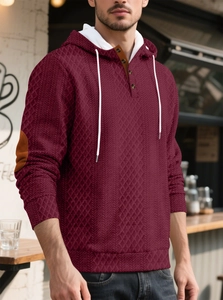 Détail du sweat à capuche bordeaux avec texture diamant, boutons henley et coudières brunes