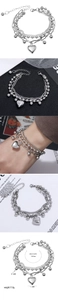 Detailed view of layered stainless steel chains and a polished heart pendant on the bracelet