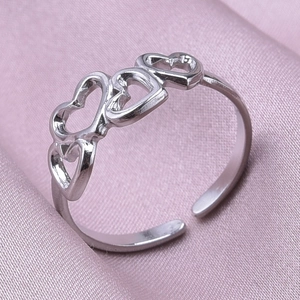 Detail of silver heart-shaped cutout ring on pink silk fabric background