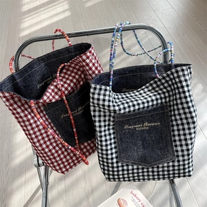 Detail of denim and plaid tote bags in red and black on a designer chair