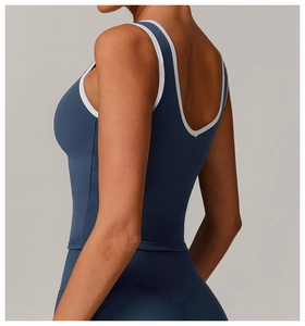 Deep U-shaped open back detail on a grey-blue tight yoga top with white contrast piping