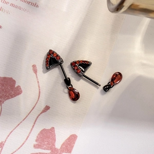 Black cat ear ear bone studs with red zircon drop pendants on decorative floral paper