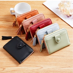 Flat lay of colorful minimalist short wallets with decorative tassels on a wooden surface