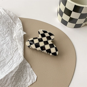 Detail of checkered claw clip on a leather pad next to a matching ceramic cup