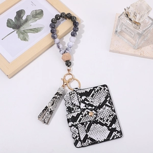 Detail of snake pattern card holder with wooden beads wristlet and leather tassel
