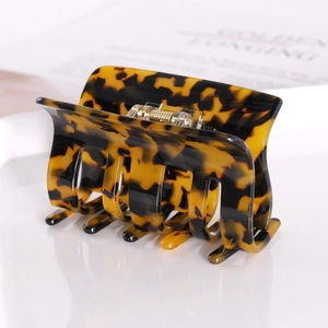 Square acetate tortoise shell hair claw clip with golden spring on a clean background