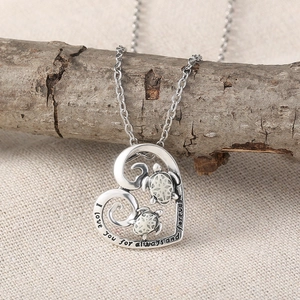 Luminous turtle heart necklace in silver finish hanging on a wooden branch