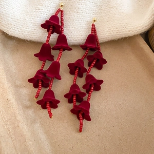 Détail des boucles d'oreilles muguet en velours rouge avec pompons perlés style vintage