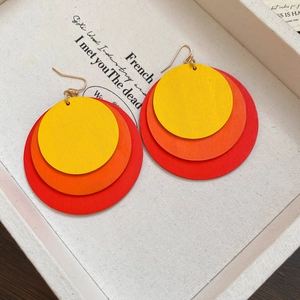 Detail of geometric round earrings with layered yellow, orange, and red wood texture