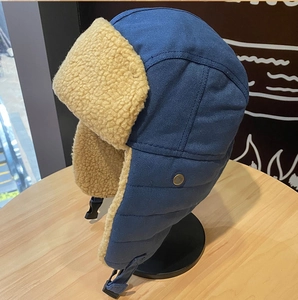 Dettaglio del cappello aviatore blu invernale con fodera in pile beige e bottone in metallo