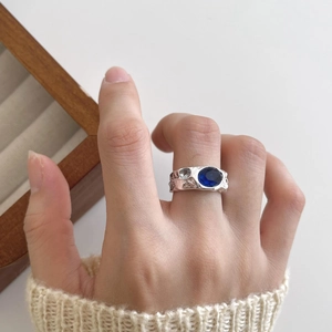 Macro detail of irregular hammered 925 silver ring featuring an oval blue gemstone