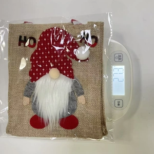 Detail of a Christmas gnome burlap gift bag being weighed on a digital scale for quality check