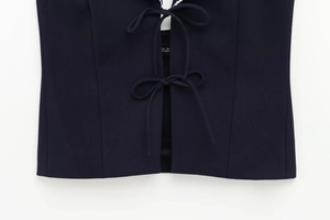 Detailed close-up of navy blue twill fabric vest with double bow tie-up front design