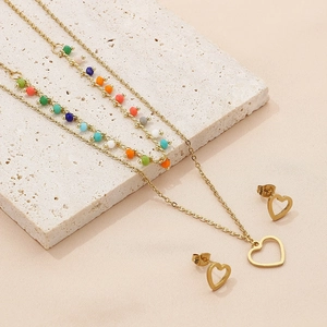 Detail of bohemian gold layered necklace with colorful beads and heart pendant on stone