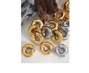Detailed view of polished gold and silver C-shaped ear cuffs on an artistic stone display