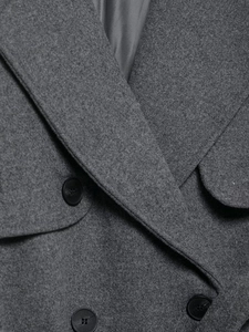 Detailed close-up of grey wool coat showing textured fabric and black button closure