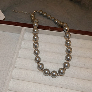 Detail of grey pearl choker necklace with gold spacer beads on a velvet jewelry tray