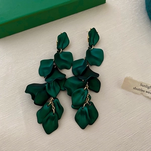 Macro detail of dark green petal tassel earrings with matte resin and gold chain links