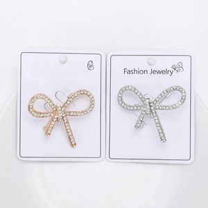 Close-up of gold and silver bow brooches with sparkling rhinestones on jewelry cards