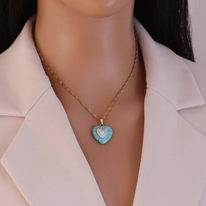 Detail of heart turquoise pendant with evil eye motif on golden rope chain necklace