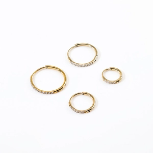 Detail of four graduated gold stainless steel hoop earrings with cubic zirconia inlay