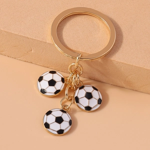Detailed shot of three mini football charms on a glossy golden keychain ring