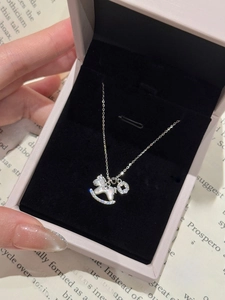 Détail du pendentif cheval à bascule en nacre et zircons dans un coffret cadeau rose