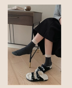 Gros plan de chaussettes en coton à rayures gris foncé avec revers côtelés beige et mules